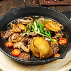 Roasted potatoes and beef meat in cast iron pan