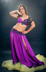 Obraz premium A belly dance soloist poses in a purple concert costume