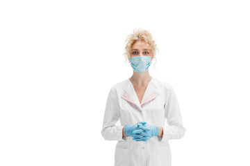 Portrait of female doctor, nurse or cosmetologist in white uniform and blue gloves over white background. Copyspace. Working in protective face mask. Concept of healthcare and medicine, beauty.