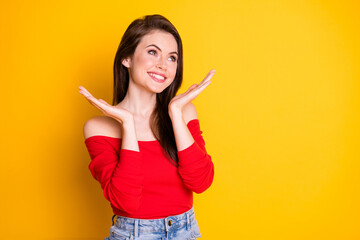 Photo of pretty adorable girlish young lady toothy shiny smiling palms face look empty space wear shirt uncovered shoulders denim skirt isolated vibrant yellow color background