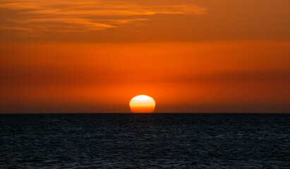 Sun hiding by the ocean