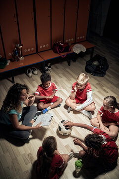 Kid's soccer team and their female coach made a relaxed atmosphere before training