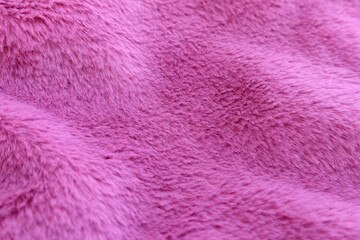 Perspective view of waves of fluffy pink faux fur, texture of fashionable fur fabric. Small dept of focus.