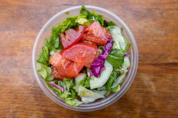 Simple Takeaway Salad in a Circular Container on a Wood Table