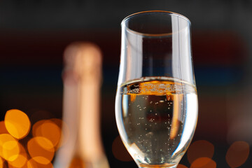 Champagne glass on blurred garland lights background