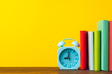 Books and alarm clock on table, education concept