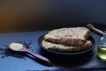 whole grains slice bread in the black dish on the black wooden table with a glass of honey during breakfast