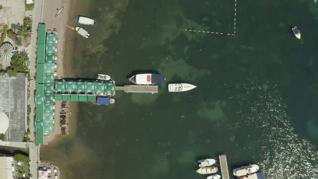 Drone video parallel to the beach and the Adriatic Sea in Budva where you can see umbrellas, sunbeds, sand and waves. Aerial view Balkans Montenegro.