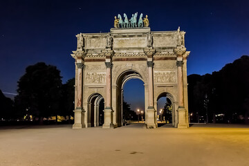 Triumphal Arch (Arc de Triomphe du Carrousel) at night in Tuileries gardens in Paris. Monument built between 1806 - 1808 to commemorate Napoleon's military victories. Paris, France.