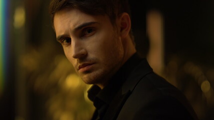 Sensual guy thinking in dark background. Focused man touching face indoors.