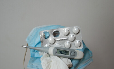 Thermometer showing high temperatures and medicines and blue mask to control and prvent covid-19 spread