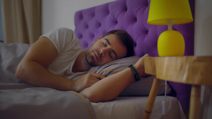 Young caucasian man falling asleep in bed in evening