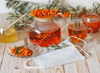 The concept of the protection and treatment of influenza with folk remedies using the beneficial sea buckthorn berries.Medical masks with sea buckthorn herbal tea, jam, honey and sea .