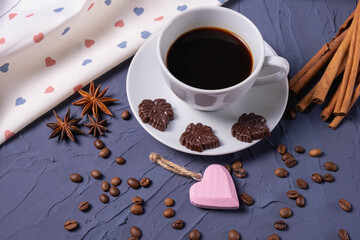 Cup of coffee, chocolate, cinnamon, coffee beans and heart shaped pendant