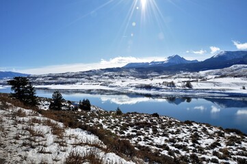 Fototapeta na wymiar Bright sunshine over mountains and snowy lake
