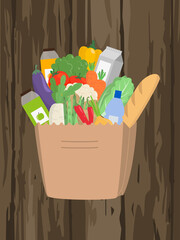 Paper bag full of food on wooden background.