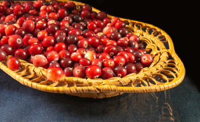 Ripe red cranberry in braided plate on table