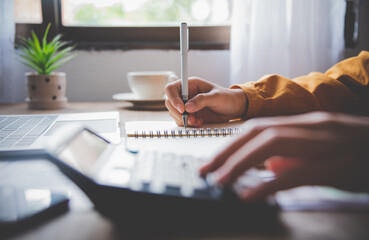  business person sitting at a desk at an office By using the calculator to work. Business Concept Analysis and Planning