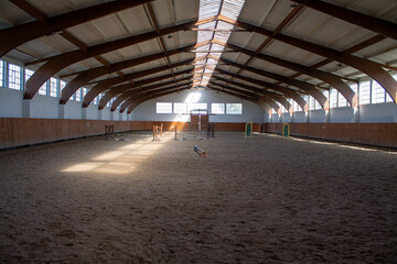 A light-flooded riding arena with some jumping obstacles.