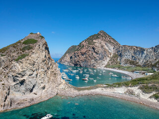 Drone view of Palmarola island with chrystalline green water and boats (Ponza, Latina, Lazio, Italy).