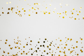 Gold and silver confetti on a white festive background. In the middle there is space for text or copy space.