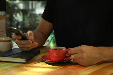 Fototapeta na wymiar Man using phone and drink coffee in restaurant