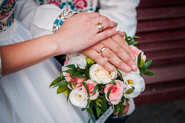 Obraz na płótnie Canvas hands of newlyweds with wedding rings on a wedding bouquet with white and pink roses
