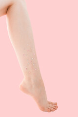 Woman's thin unshaven leg with sparkles on a pink background. Feminism