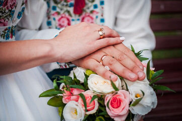 Obraz na płótnie Canvas hands of newlyweds with wedding rings on a wedding bouquet with white and pink roses