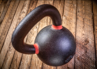 Fototapeta na wymiar heavy iron kettlebell floating over rustic wood background - fitness concept, soft focus image shot with lensless pinhole camera