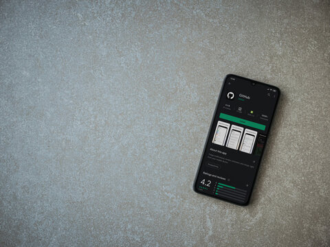 Lod, Israel - July 8, 2020: GitHub app play store page on the display of a black mobile smartphone on ceramic stone background. Top view flat lay with copy space.