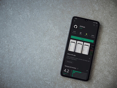 Lod, Israel - July 8, 2020: GitHub app play store page on the display of a black mobile smartphone on ceramic stone background. Top view flat lay with copy space.