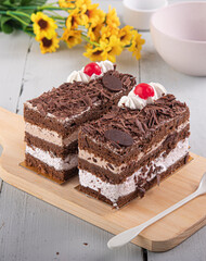 Black Forest Cake served on a white wood table with flower on the side