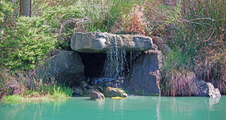 Panoramic view of an impressive garden landscape with a lagoon and an artificial waterfall