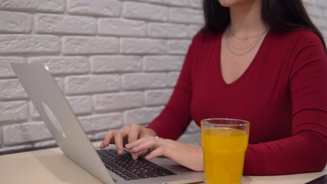 Woman office worker using laptop, typing hands, drinking fresh, distance work