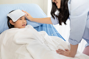 Fototapeta premium close up asian girl have a fever, she's lying on bed in hospital with her mother support and watched her closely