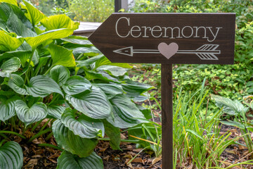 wood sign in a garden with the word Ceremony and an arrow with a pink heart