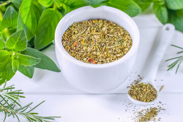 dried oregano in a white bowl close-up. background with fresh oregano and dried herbs. sprigs of fresh oregano on a white background and a bowl of spices.