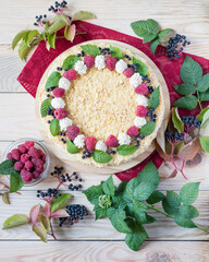 Napoleon cake with raspberries and cream on red napkin on light wooden background. Overhead view, vertical orientation