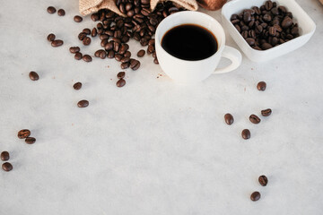 A cup of coffee and coffee beans on white, marble background