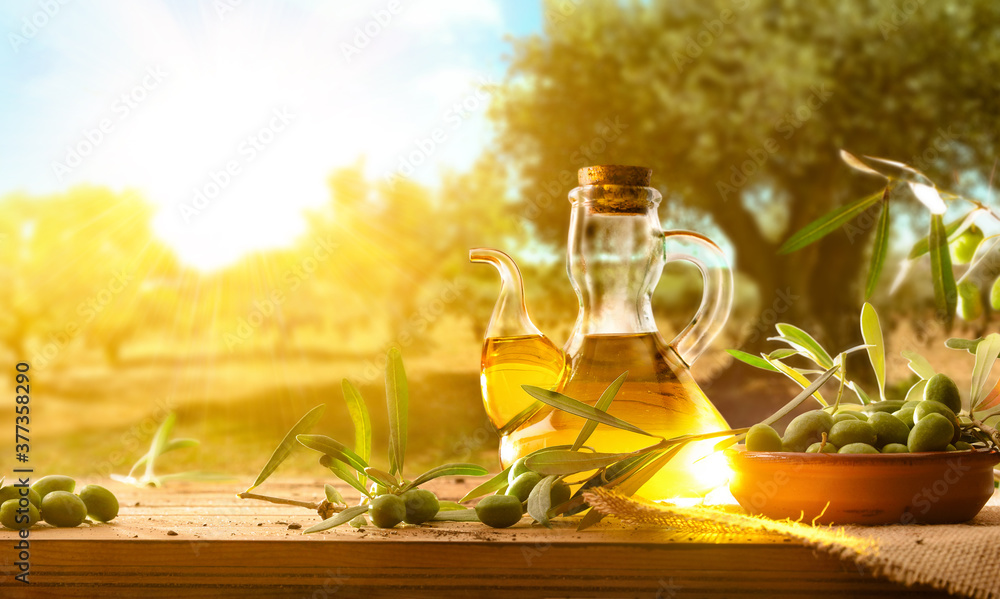 Wall mural Olives on wooden table with oil in field