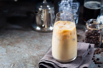 Ice coffee cold summer drink in a tall glass and coffee beans on a stone background.