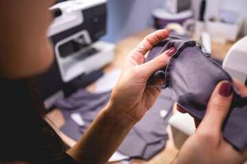Selective focus of seamstress checking seam on cloth while working at table 