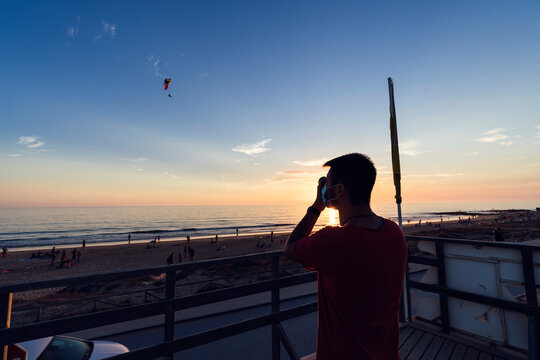 Silueta de chico fotografiando parapente en cadiz