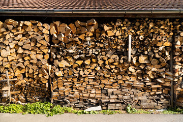 chopped and cut beautiful brown firewood protected from rain and bad weather in storage under a brick roof, for a warm winter