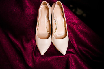 Beige shoes are presented on a pink fabric