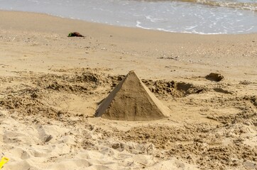 Fototapeta na wymiar Sand pyramid on the beach by the sea