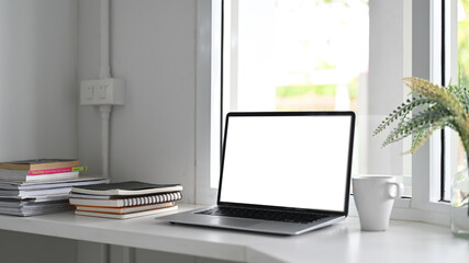 Naklejka premium Laptop computer on white table with book, magazine and coffee cup.
