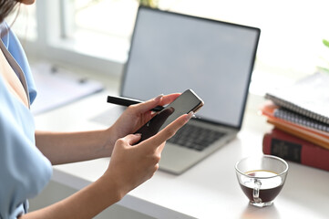 Cropped image woman holding her mobile phone on office desk.