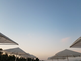 Fototapeta na wymiar Beach umbrellas against the sky. Sunset on the sea.